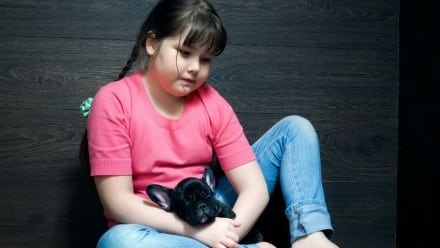 Girl sitting with her puppy looking sad