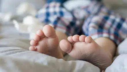 A young boy laying down on a bed in his pjs