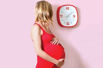 pregnant woman looking at clock
