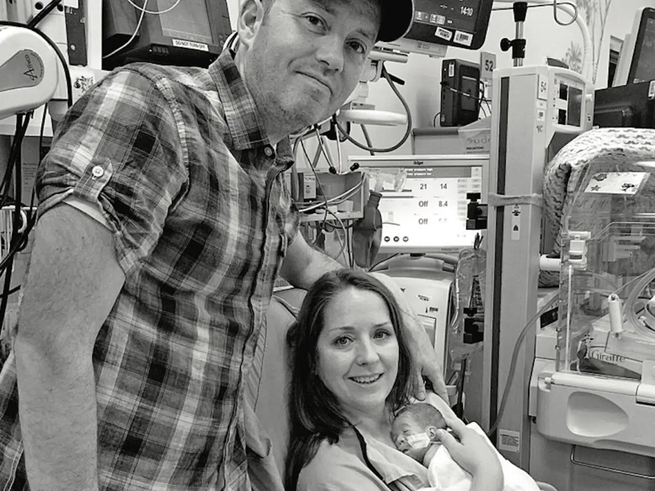 Two parents smiling while holding their newborn