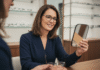Comment choisir le bon opticien pour des lunettes sur mesure ? Femme souriante essayant des lunettes élégantes en boutique